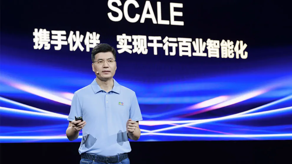 Orateur sur scène devant un écran géant affichant le mot SCALE et un slogan en chinois