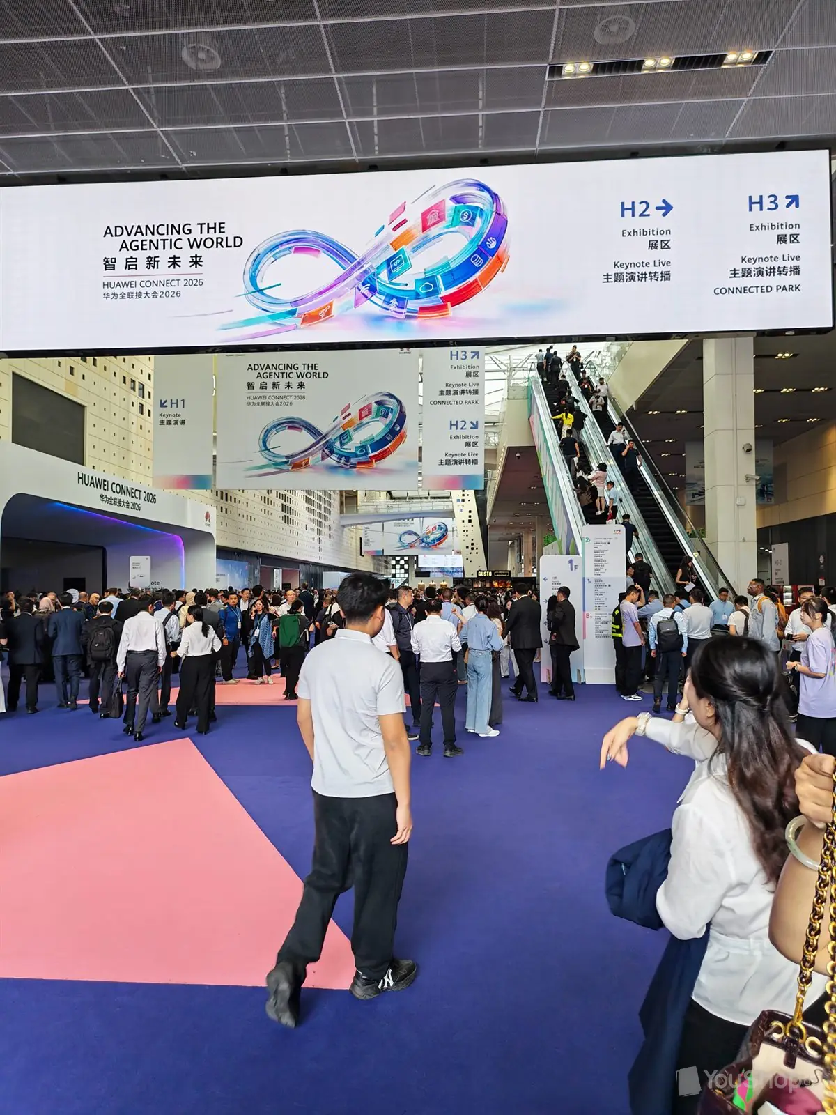 Hall d'accueil bondé, bandeau LED du salon et fléchage vers les halls H1, H2 et H3