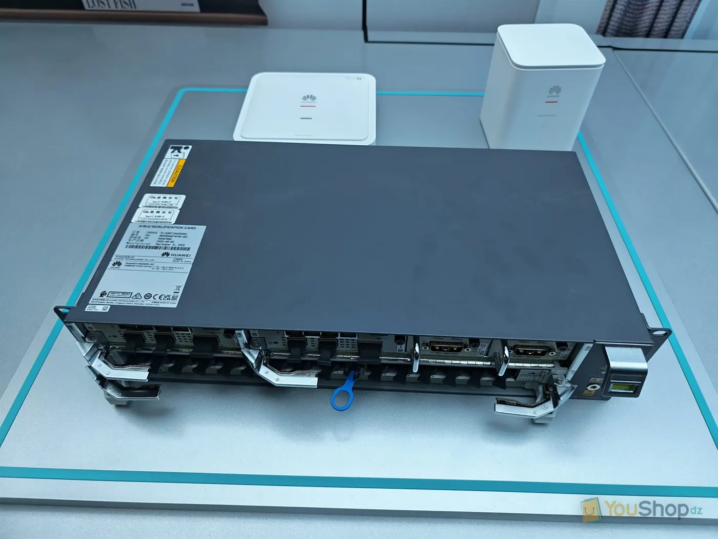 Châssis OLT SmartAX MA5800-X2 posé à plat, cartes visibles, avec un point d’accès blanc derrière
