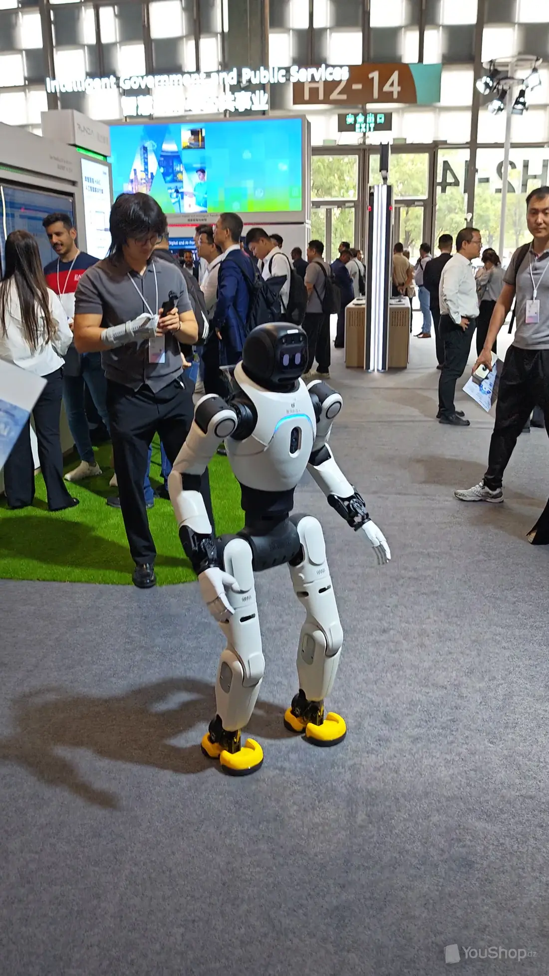 Robot humanoïde blanc marchant dans une allée du salon sous l’enseigne Intelligent Government